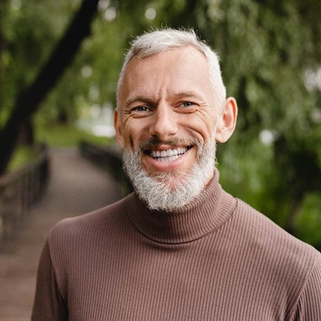 Senior man with beard smiling while on a walk