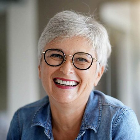 Smiling senior woman with glasses and denim jacket